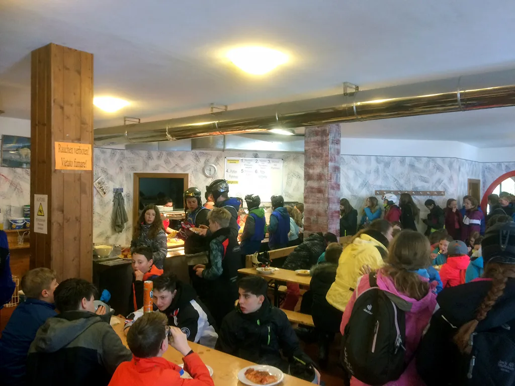 Jugendliche essen in der vollen Skihütte zu Mittag.